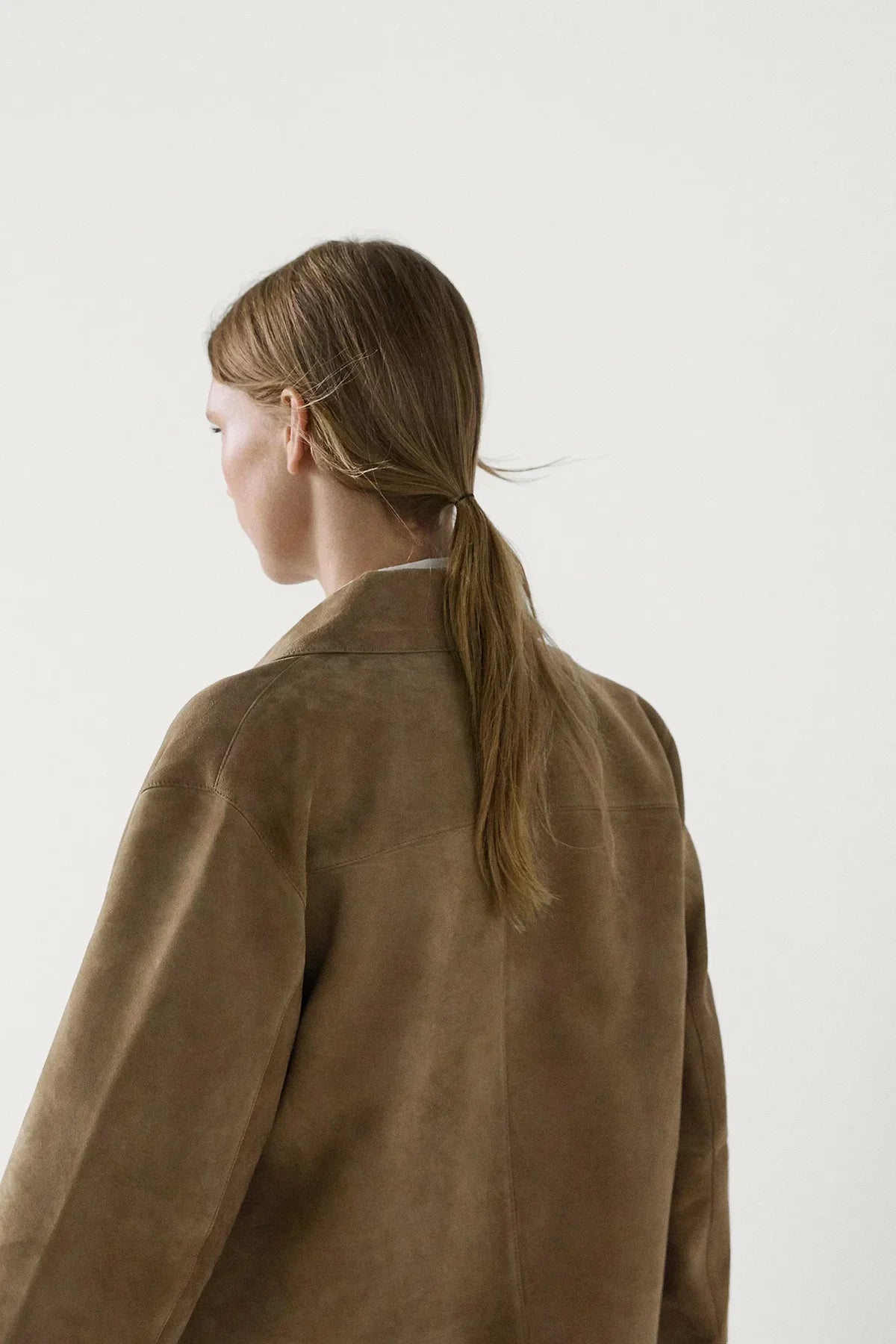 sand - Women's tan cropped faux suede jacket featuring a point collar, dark button-front closure, and two front flap pockets, styled over white tailored shorts.