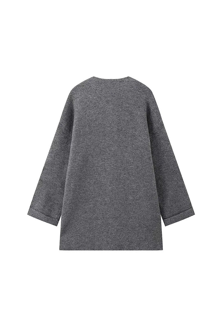 Grey - A woman wearing a thick, taupe oversized longline winter coat featuring a built-in scarf neckline, dark button closures, and large patch pockets.