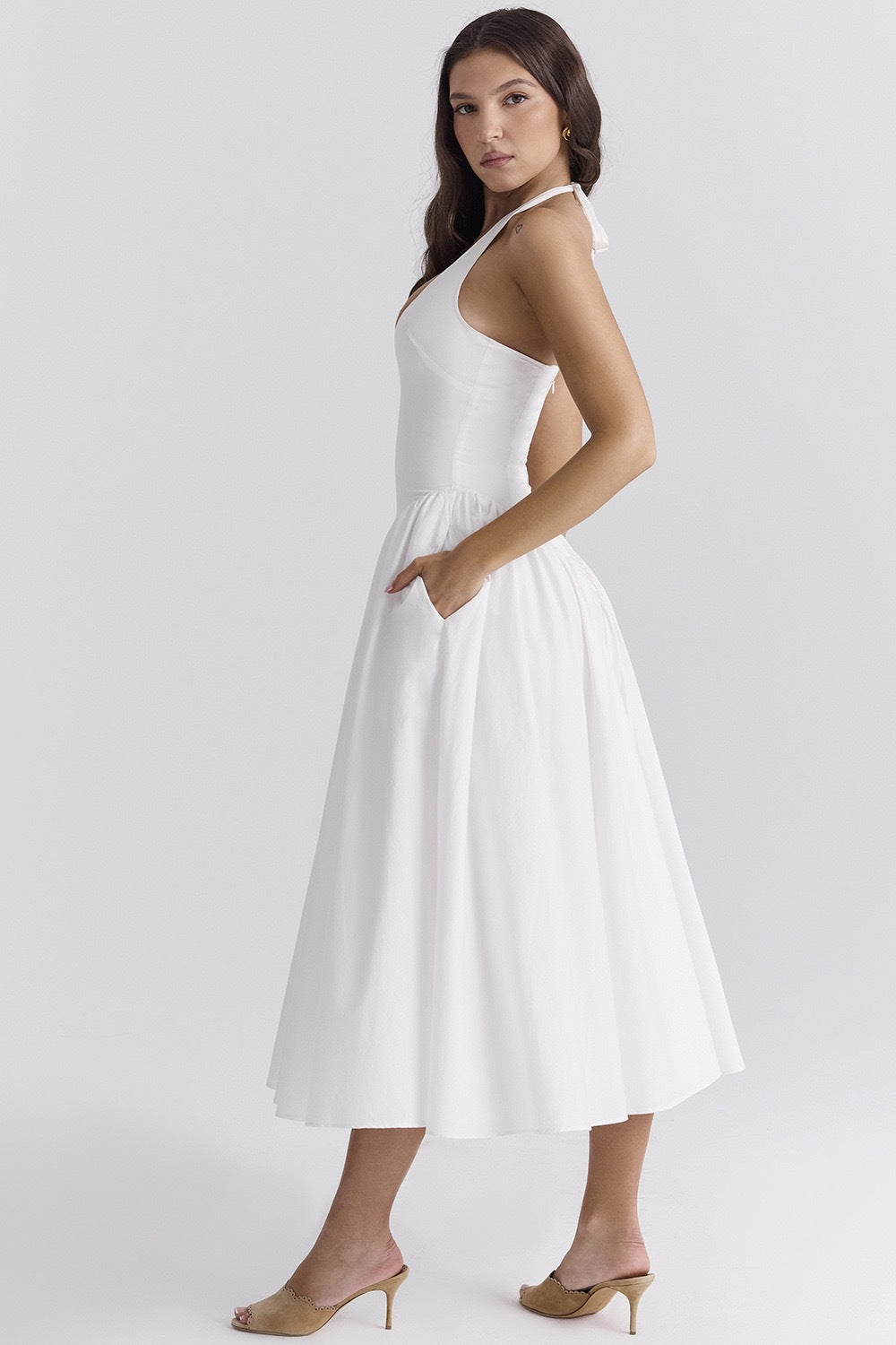 White - A woman models a white sleeveless midi dress with a deep V-neck halter top, a fitted bodice, and a full, gathered A-line skirt, against a plain white background.