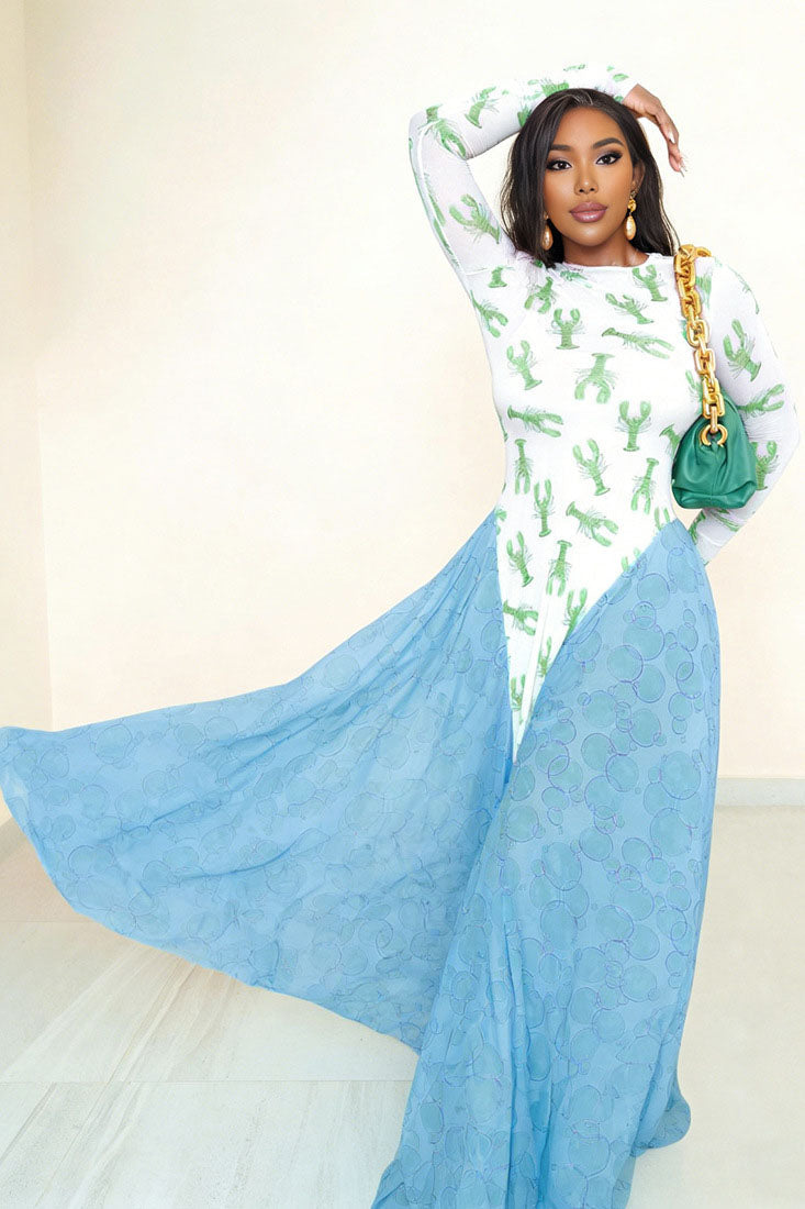Woman in pink lobster print mesh dress with green flowing skirt and a green purse.