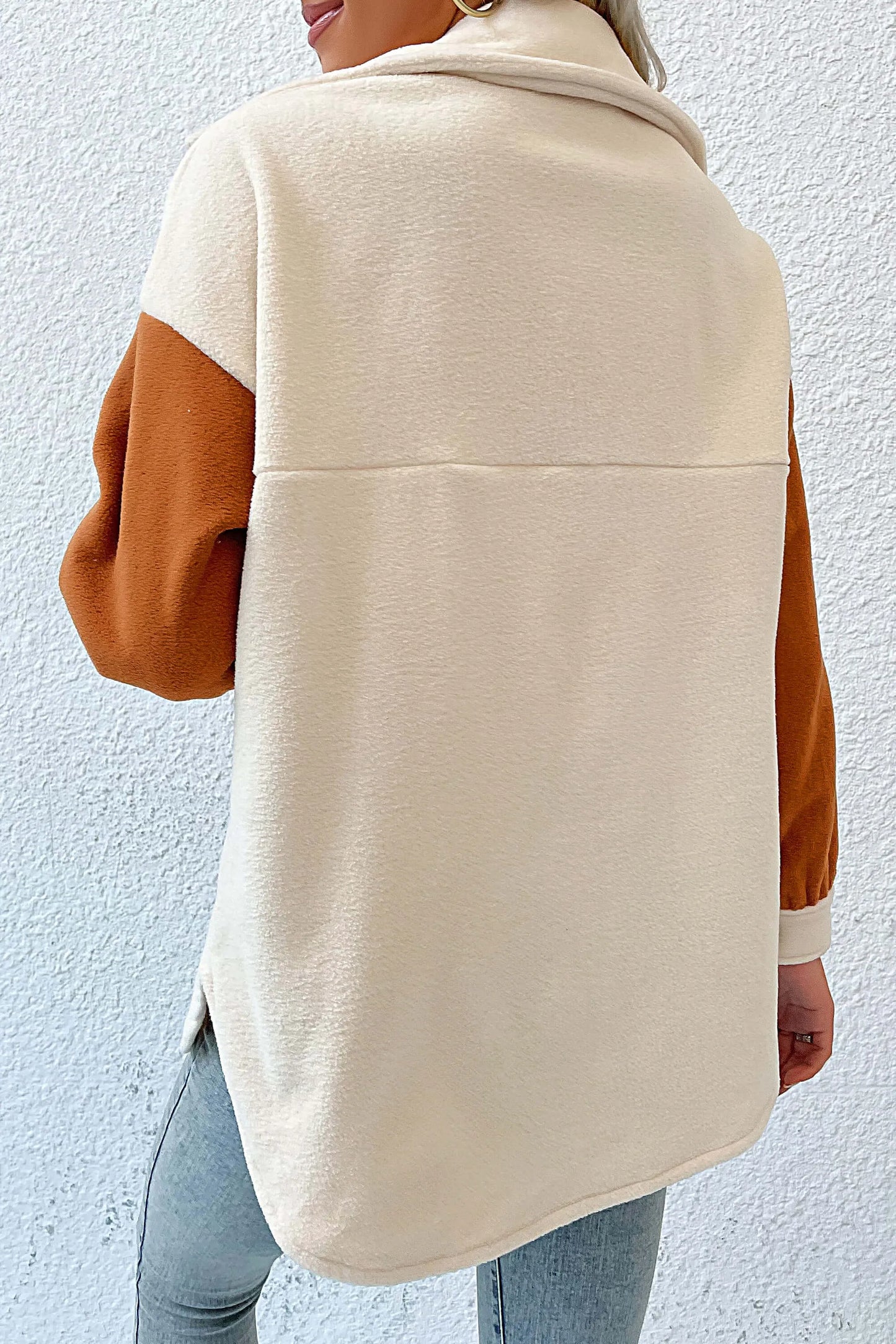Cream - A woman wearing a relaxed fit, button-front shacket featuring a cream body with contrasting rust orange sleeves and chest pocket flaps, styled open over a white crop top and blue jeans.