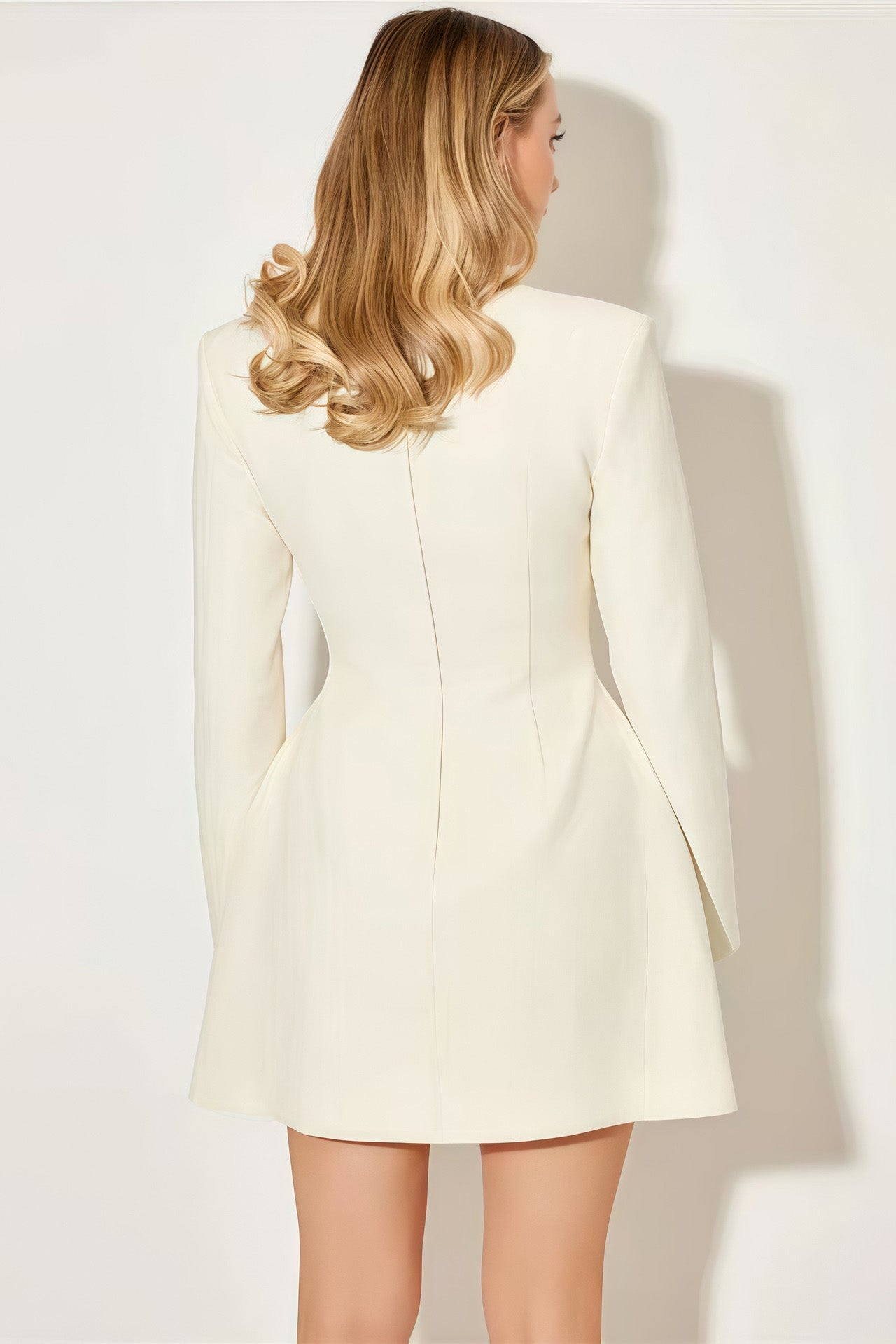 White - A woman models a long-sleeve, black mini blazer dress with a high split funnel neck, structured shoulders, and a single-breasted button front against a plain white background.