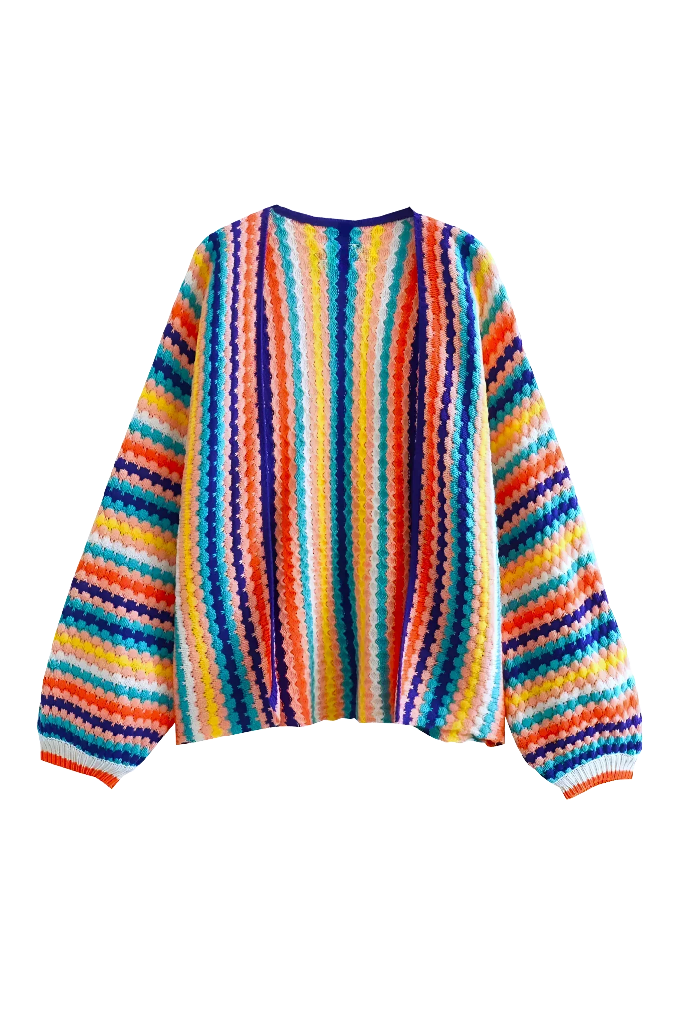 Rainbow - A woman wearing a vibrant, striped open-front crochet cardigan with ribbed cuffs, styled over a ribbed top and dark denim jeans on a city street.