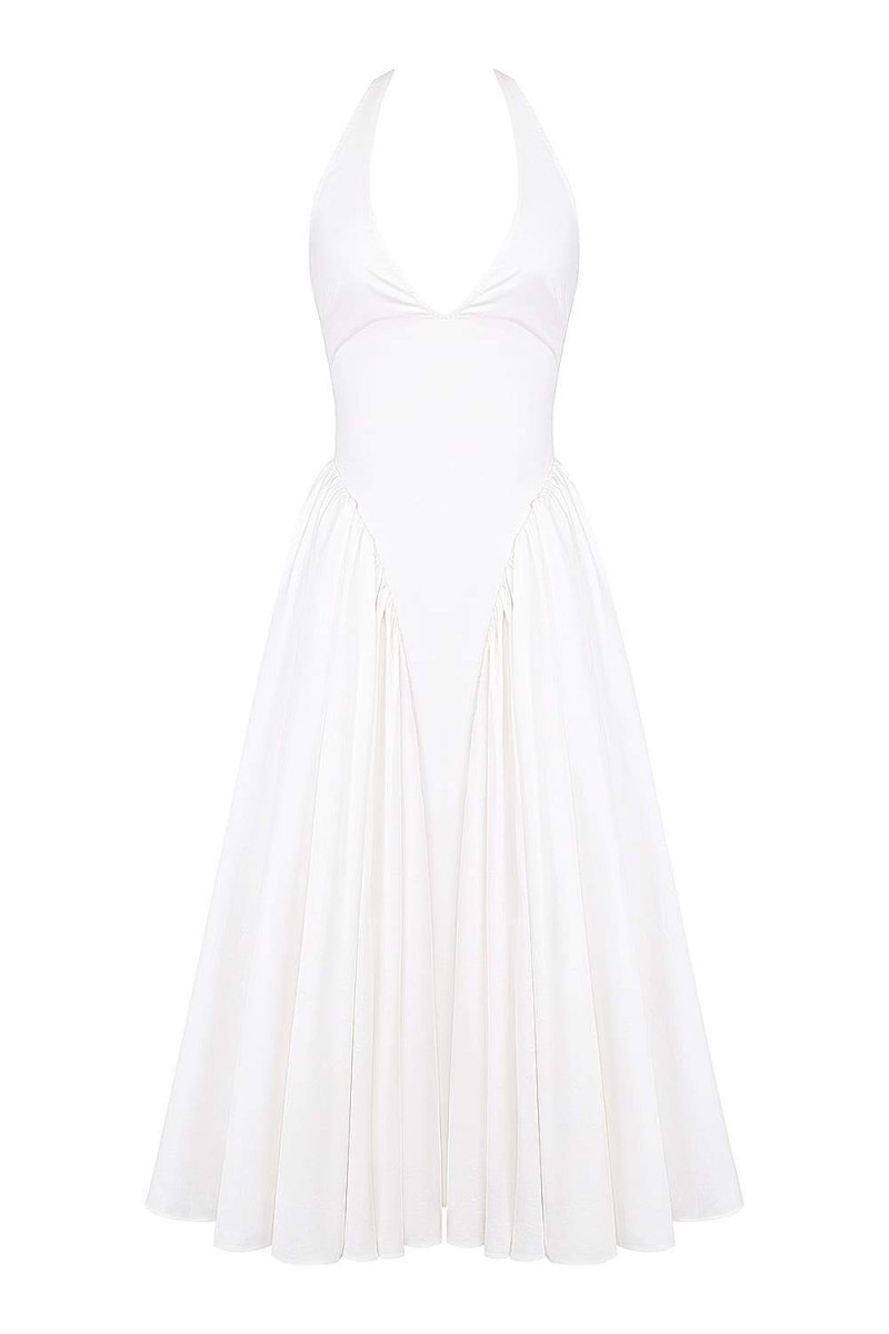 A woman models a white halter midi dress with a plunging neckline and a voluminous full skirt in an outdoor garden setting.