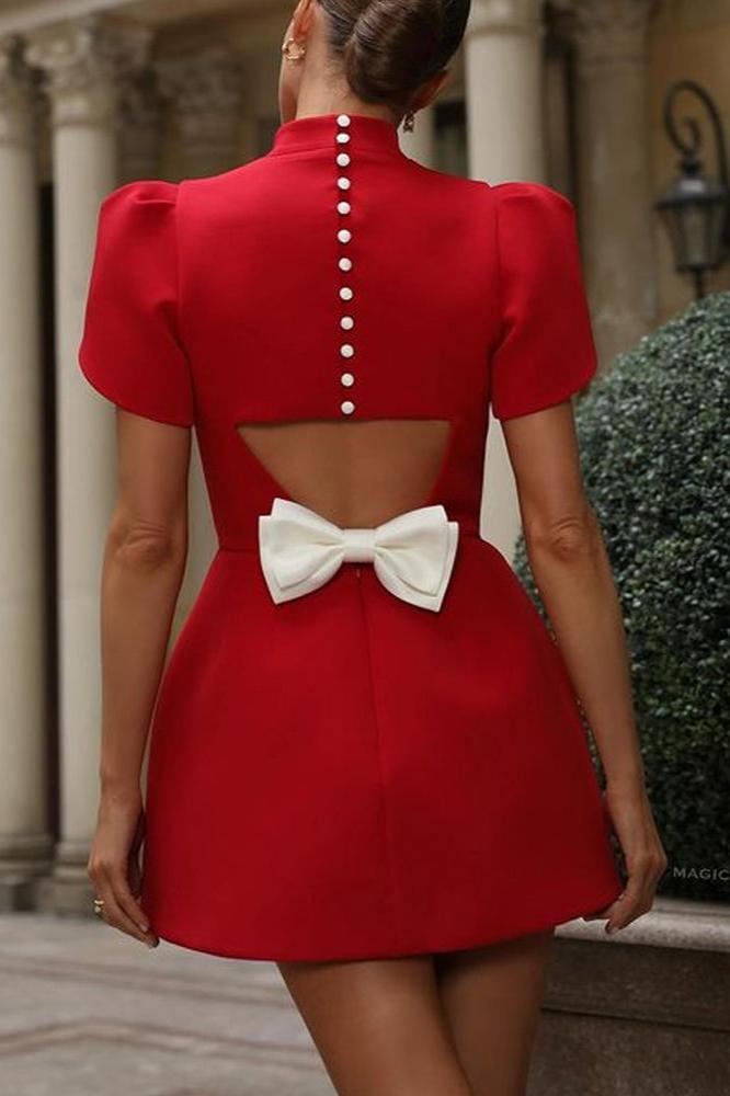 Back view of a woman wearing a short-sleeve, high-neck mini dress with a button-up back, an open-back cutout, and a large bow at the waist.