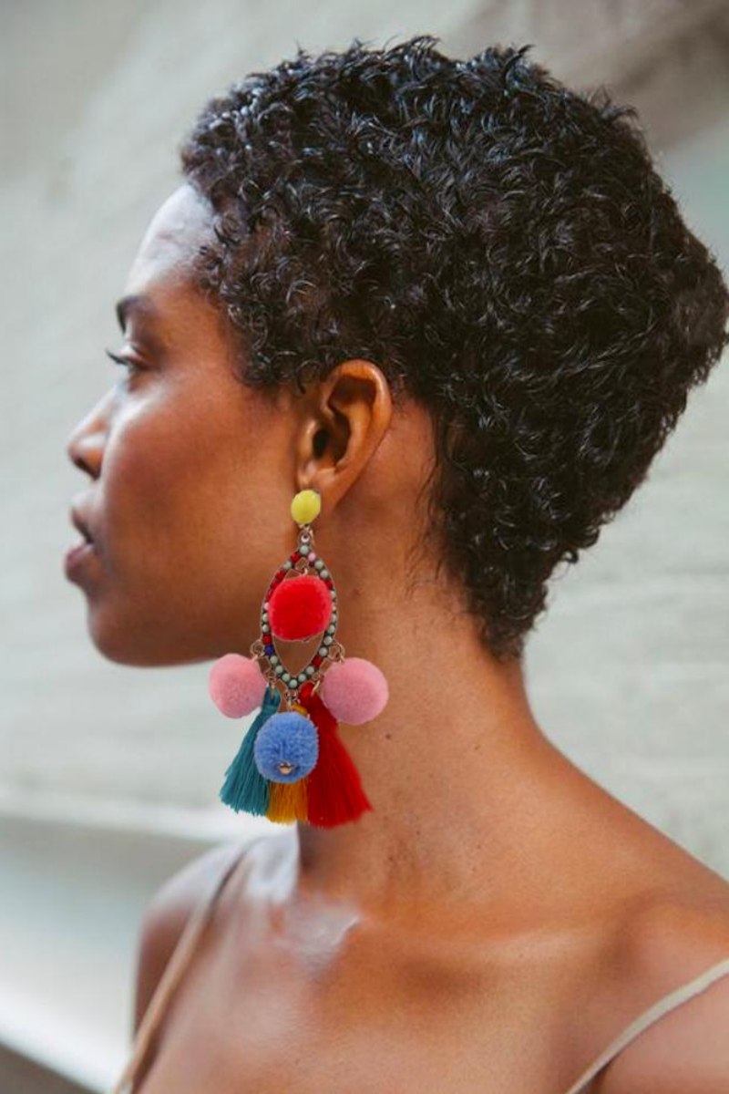 Women's vibrant statement dangle earrings featuring a beaded teardrop frame, colorful red, pink, and blue pom-poms, and sweeping red, yellow, and teal thread tassels.