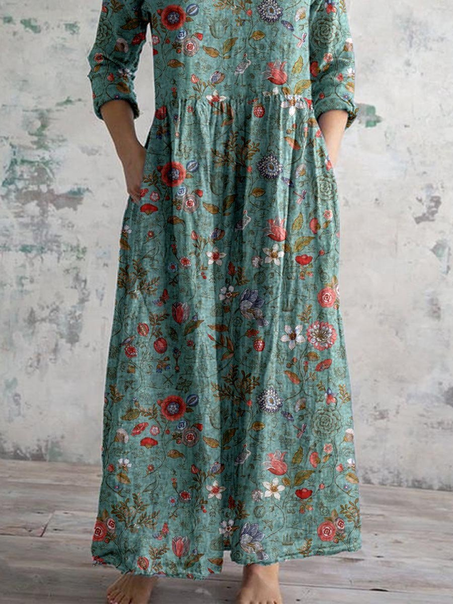 3XL - A woman wearing a teal botanical print linen maxi dress with three-quarter sleeves, a V-neckline, and side pockets, showcasing a relaxed bohemian silhouette.