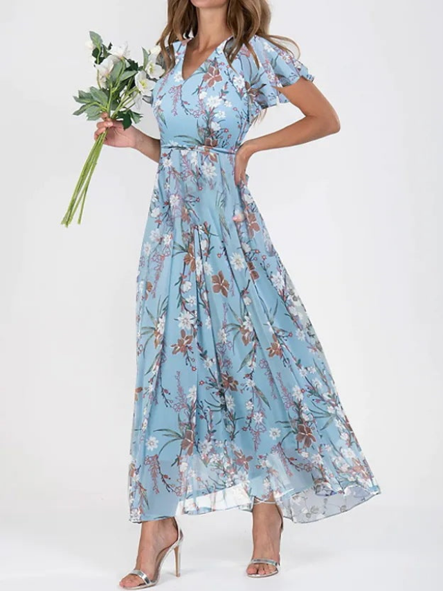 Light Blue 2 - A woman wearing a peach-colored floral print chiffon maxi dress with flutter sleeves and a V-neck, showcasing a fluid, sweeping skirt.