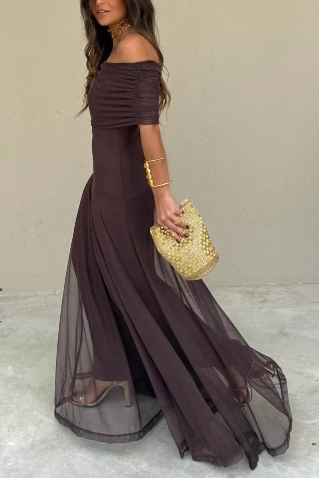 Brown - A woman wearing an elegant off-the-shoulder floor-length maxi dress featuring a ruched bodice and a sheer mesh overlay, styled with gold accessories.