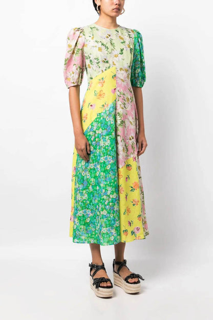 A woman models a short-sleeve, crewneck midi dress with a white background and a colorful, illustrative print of marine life including jellyfish, coral, and seashells.