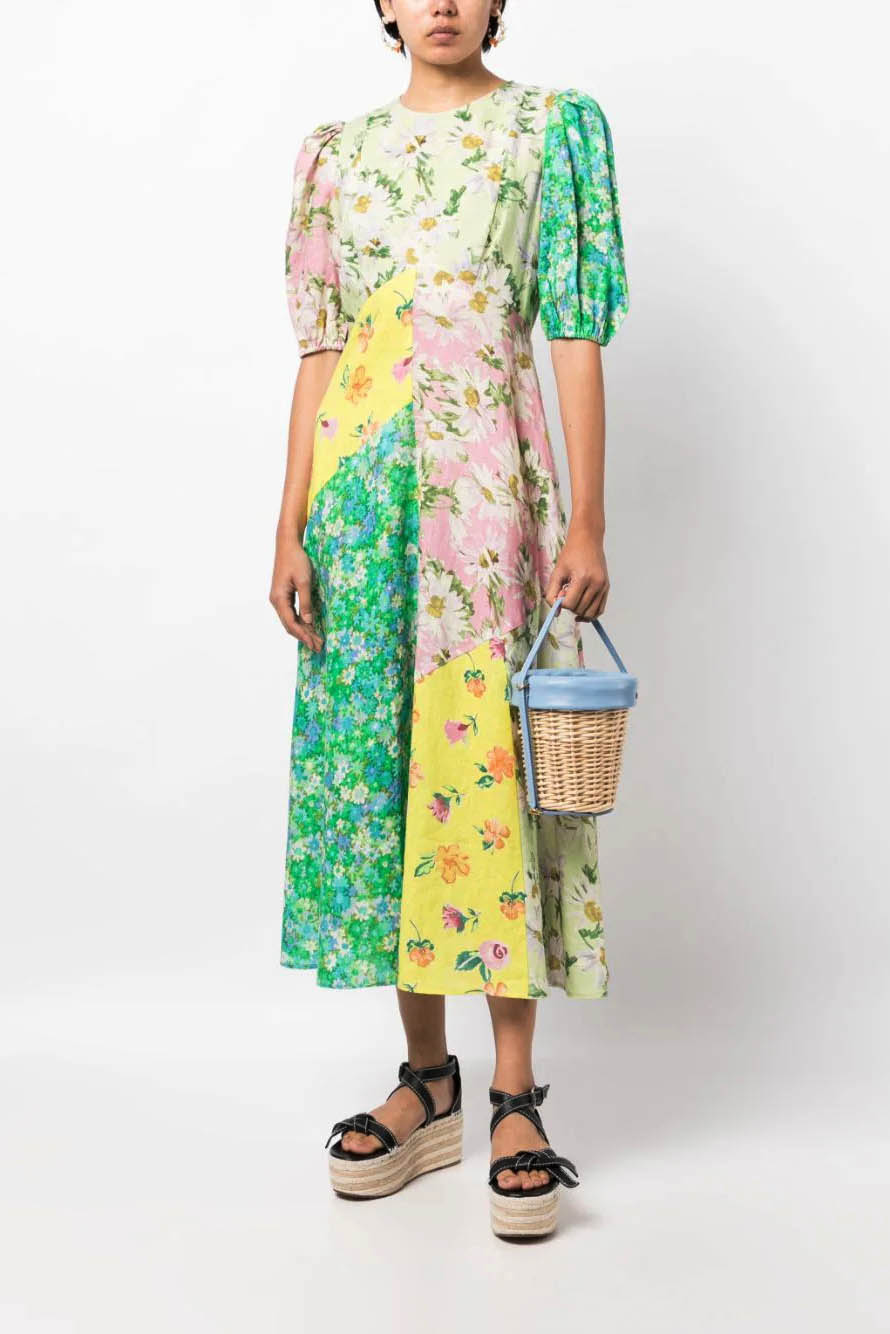 A woman models a short-sleeve, crewneck midi dress with a white background and a colorful, illustrative print of marine life including jellyfish, coral, and seashells.