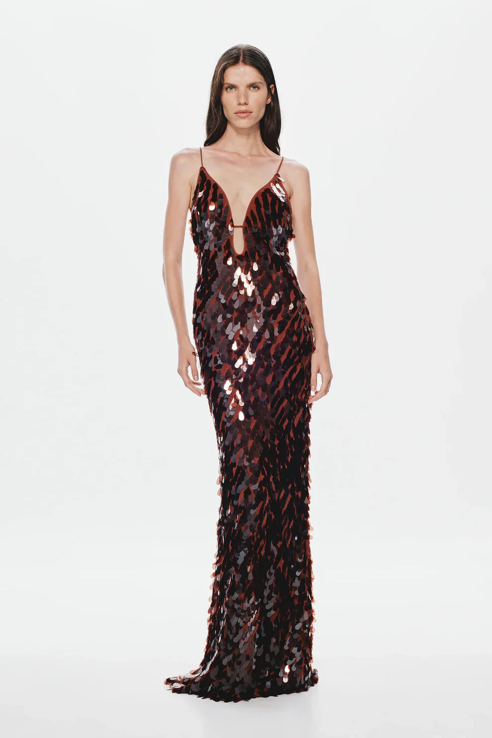 A woman models a floor-length, dark formal gown covered in large, reflective metallic teardrop sequins, featuring a deep plunging V-neckline and thin spaghetti straps against a plain white background.