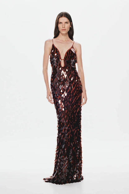 A woman models a floor-length, dark formal gown covered in large, reflective metallic teardrop sequins, featuring a deep plunging V-neckline and thin spaghetti straps against a plain white background.