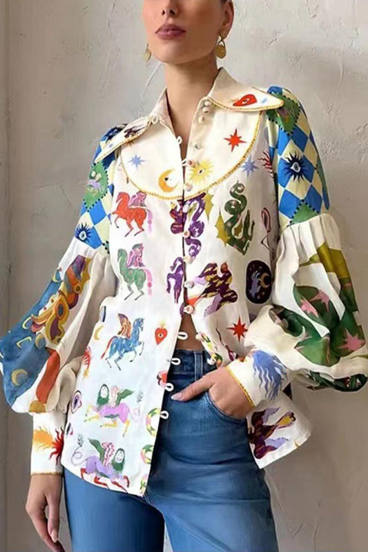 Woman wearing a white long-sleeve blouse with a large pointed collar, voluminous balloon sleeves, and a colourful, eclectic print featuring horses, suns, and checkerboard patterns, paired with blue jeans.