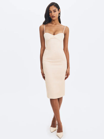 A woman modeling a fitted cream-colored midi dress with spaghetti straps and a ruched sweetheart neckline.