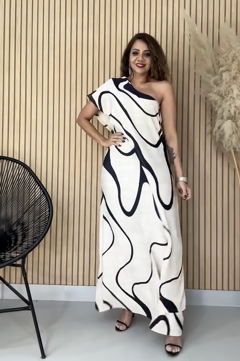 Woman in cream and black abstract print one-shoulder maxi dress