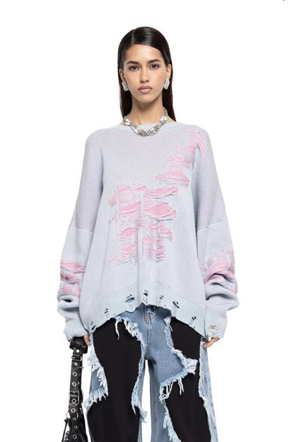 Grey - Model wearing a women's oversized black knit jumper featuring heavy distressed laddering and cut-outs, styled with a white mini skirt.