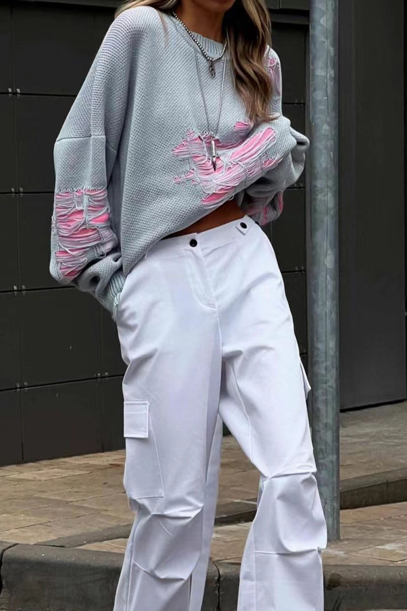 Grey - Model wearing a women's oversized black knit jumper featuring heavy distressed laddering and cut-outs, styled with a white mini skirt.