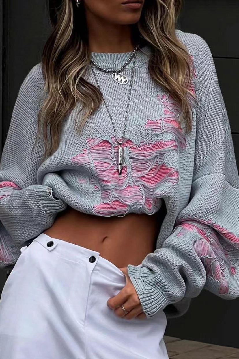 Grey - Model wearing a women's oversized black knit jumper featuring heavy distressed laddering and cut-outs, styled with a white mini skirt.