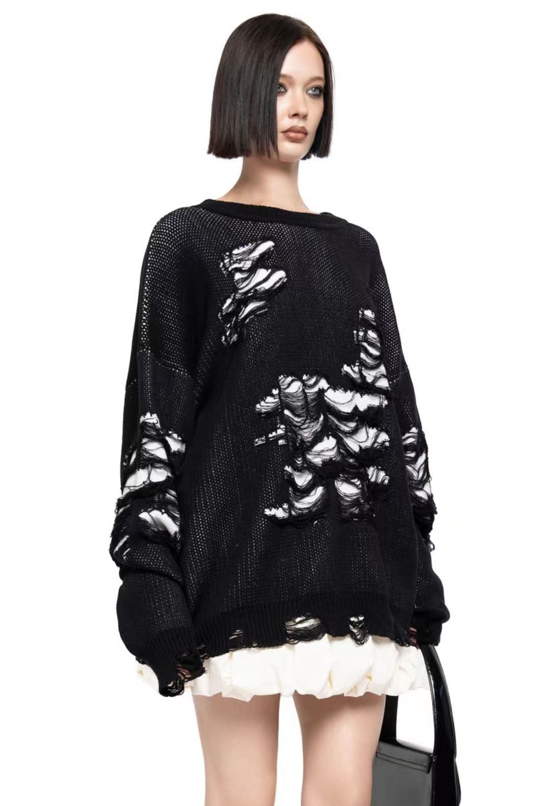 Black - Model wearing a women's oversized black knit jumper featuring heavy distressed laddering and cut-outs, styled with a white mini skirt.