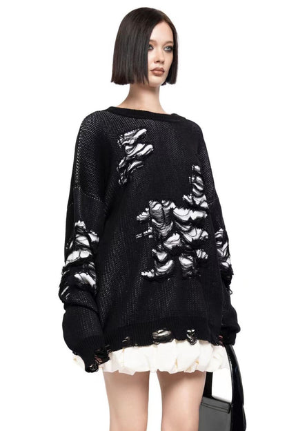 Black - Model wearing a women's oversized black knit jumper featuring heavy distressed laddering and cut-outs, styled with a white mini skirt.