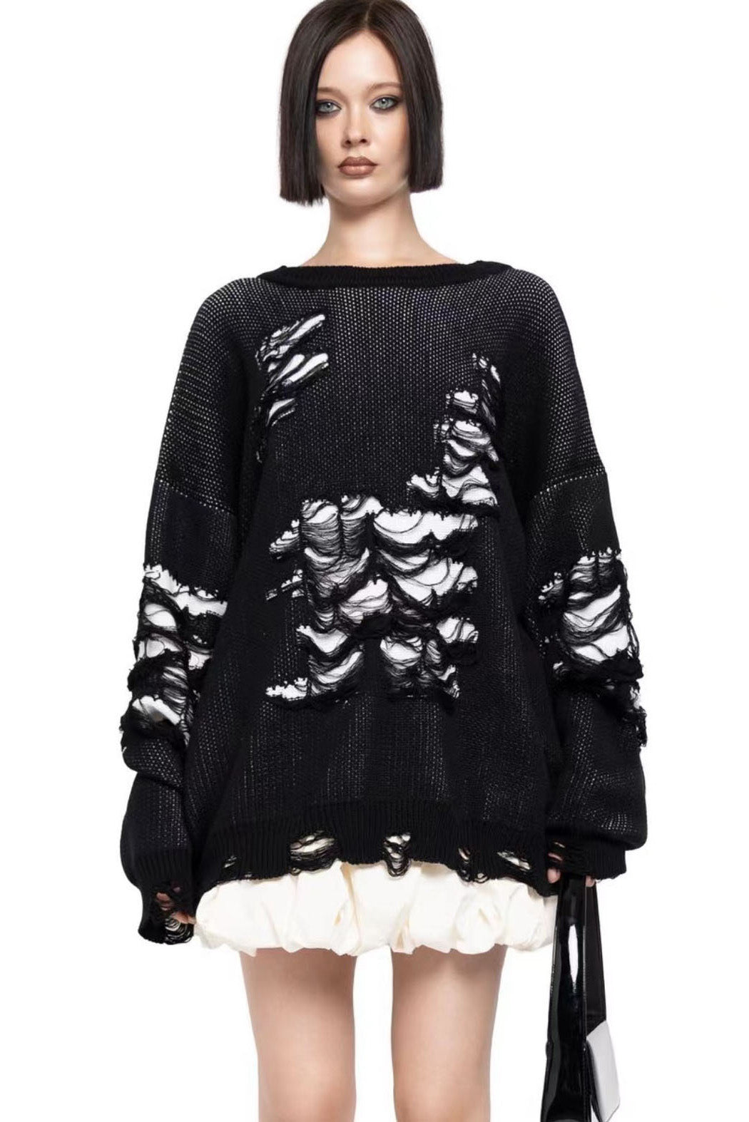 Black - Model wearing a women's oversized black knit jumper featuring heavy distressed laddering and cut-outs, styled with a white mini skirt.