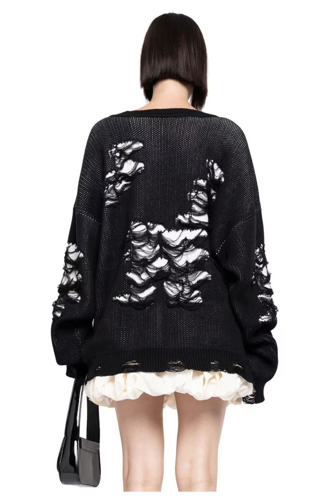 Black - Model wearing a women's oversized black knit jumper featuring heavy distressed laddering and cut-outs, styled with a white mini skirt.