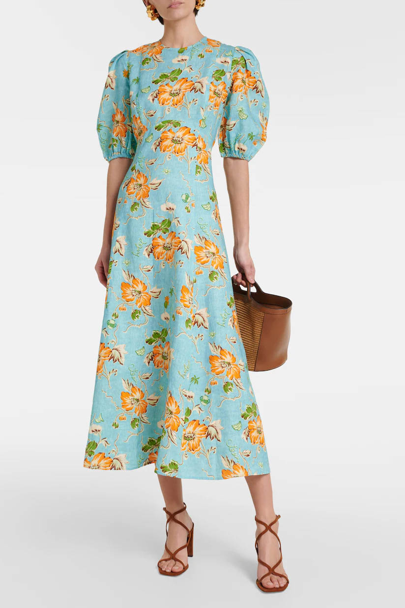 A woman models a short-sleeve, crewneck midi dress with a white background and a colorful, illustrative print of marine life including jellyfish, coral, and seashells.