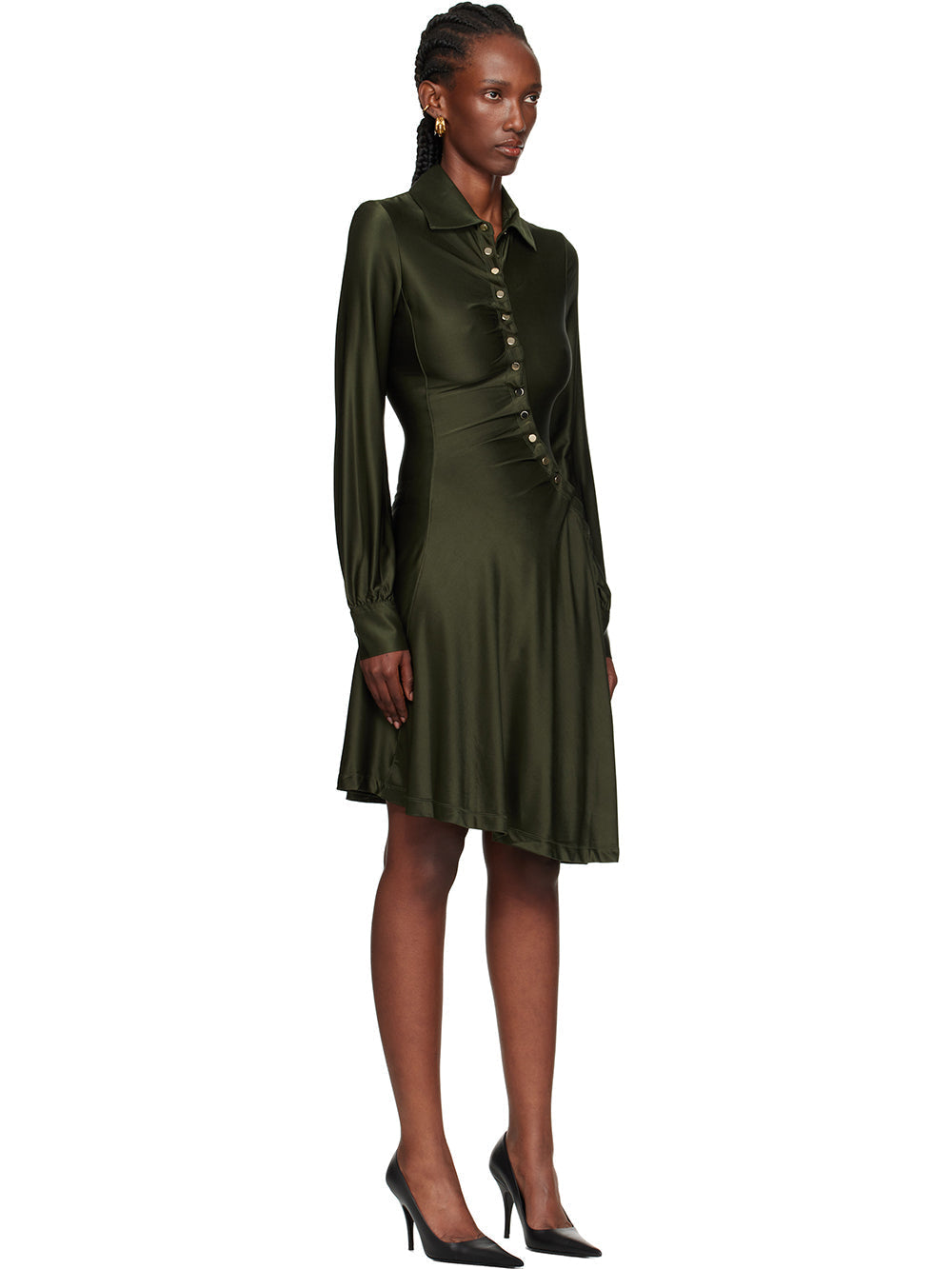 Black - Full-length view of a woman wearing a long-sleeved, knee-length shirt dress in a lustrous olive green, featuring an asymmetrical button front, ruched detailing, and an uneven hem.