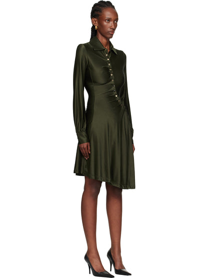 Black - Full-length view of a woman wearing a long-sleeved, knee-length shirt dress in a lustrous olive green, featuring an asymmetrical button front, ruched detailing, and an uneven hem.