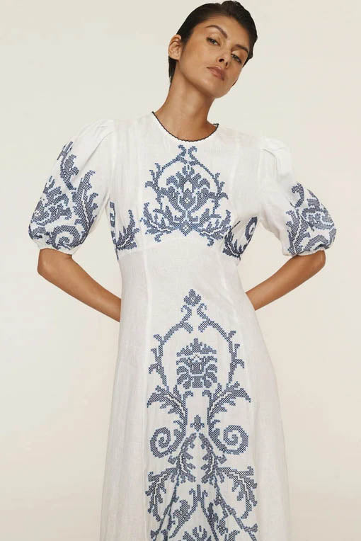 A woman models a short-sleeve, crewneck midi dress with a white background and a colorful, illustrative print of marine life including jellyfish, coral, and seashells.