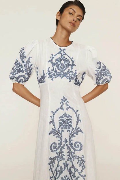 A woman models a short-sleeve, crewneck midi dress with a white background and a colorful, illustrative print of marine life including jellyfish, coral, and seashells.