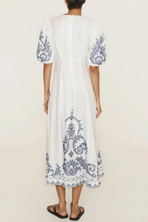 A woman models a short-sleeve, crewneck midi dress with a white background and a colorful, illustrative print of marine life including jellyfish, coral, and seashells.