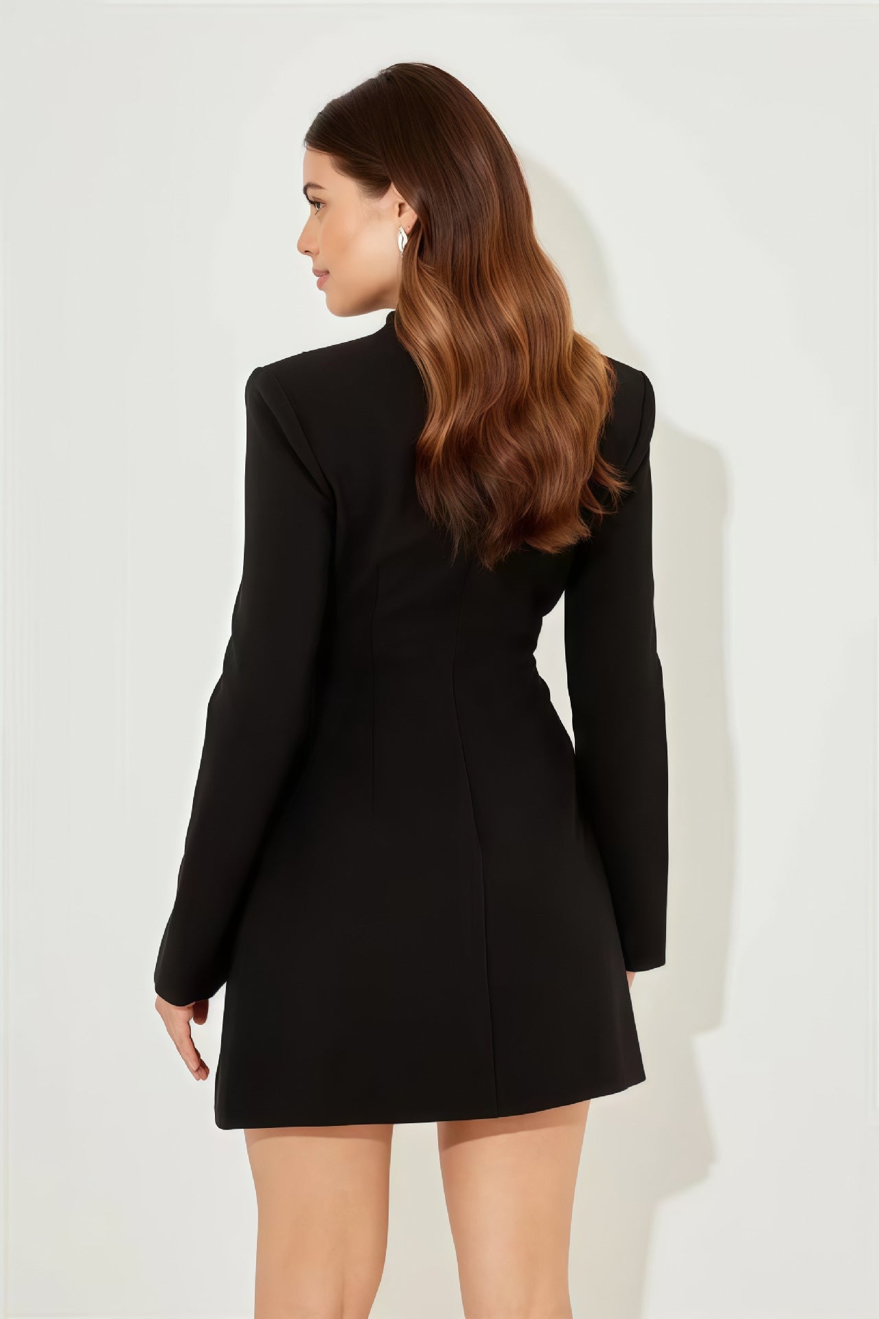 Black - A woman models a long-sleeve, black mini blazer dress with a high split funnel neck, structured shoulders, and a single-breasted button front against a plain white background.