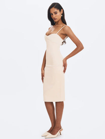 A woman modeling a fitted cream-colored midi dress with spaghetti straps and a ruched sweetheart neckline.