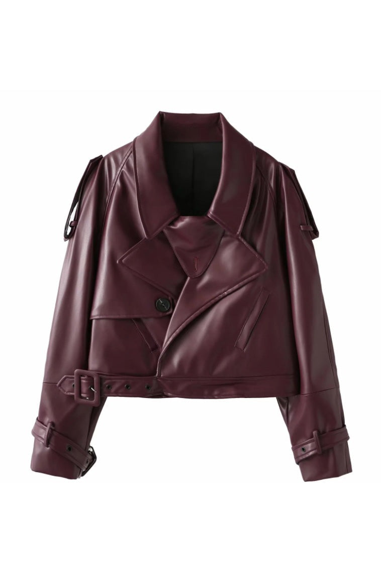 Red - A woman wearing a burgundy oversized faux leather jacket with wide lapels, belted cuffs, and voluminous sleeves, styled over a black turtleneck in a city setting.