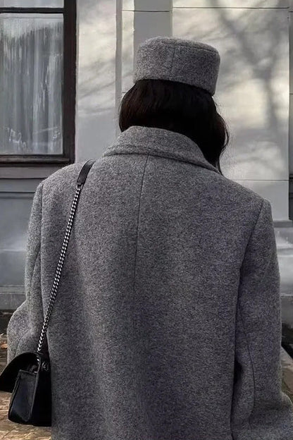 Grey - A woman wearing a long, oversized grey double-breasted maxi coat with wide lapels and flap pockets, styled for winter.