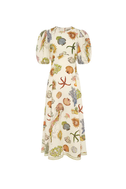 A woman models a short-sleeve, crewneck midi dress with a white background and a colorful, illustrative print of marine life including jellyfish, coral, and seashells.