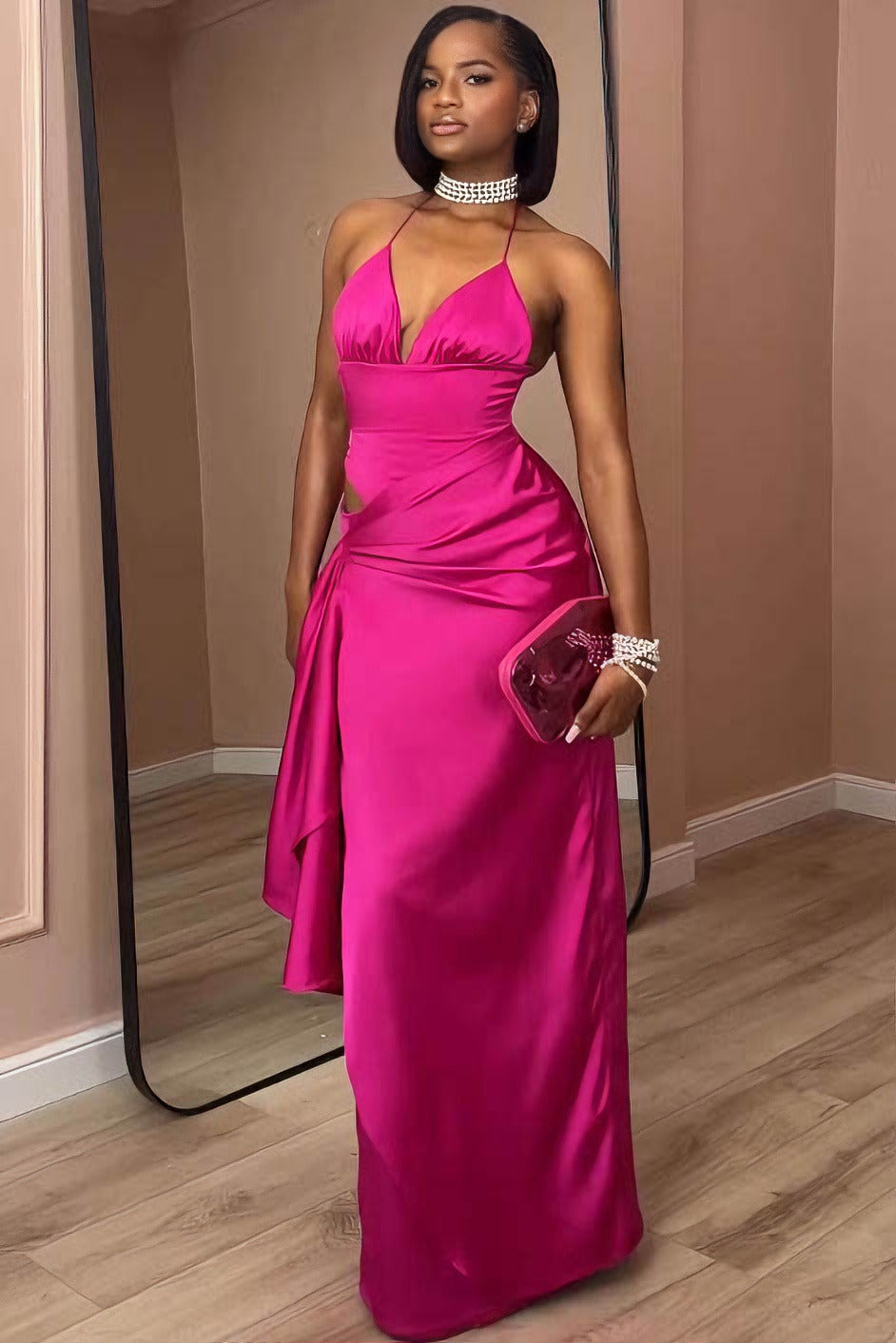 Pink - A woman modeling a formal, bright pink satin maxi gown featuring a halter neckline, a side cutout at the waist, and elegant draped detailing.