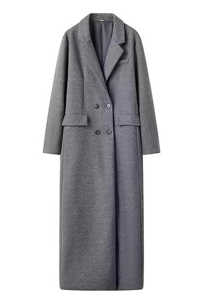 Grey - A woman wearing a long, oversized grey double-breasted maxi coat with wide lapels and flap pockets, styled for winter.