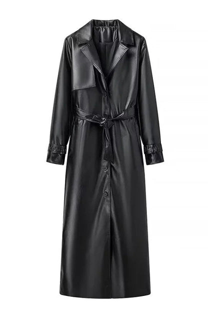 Black - A woman walking down a city street wearing a long, deep burgundy faux leather trench coat with a tie belt, styled over a black turtleneck and black leggings.