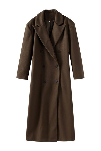 Brown - A woman wearing an oversized, dark brown double-breasted maxi coat with a notched lapel, styled over a beige sweater and light skirt.