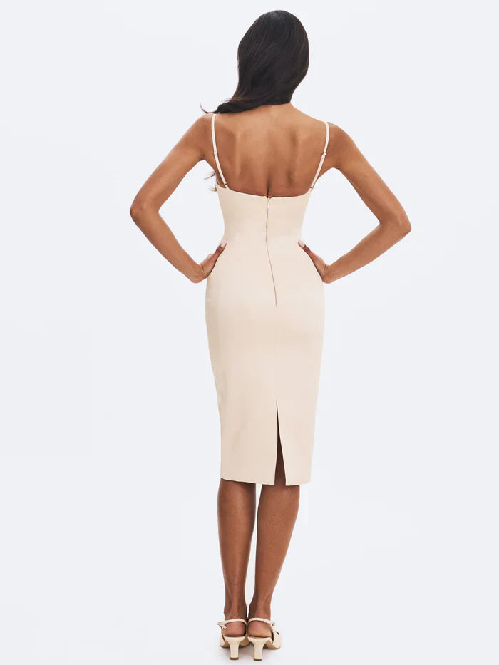 A woman modeling a fitted cream-colored midi dress with spaghetti straps and a ruched sweetheart neckline.