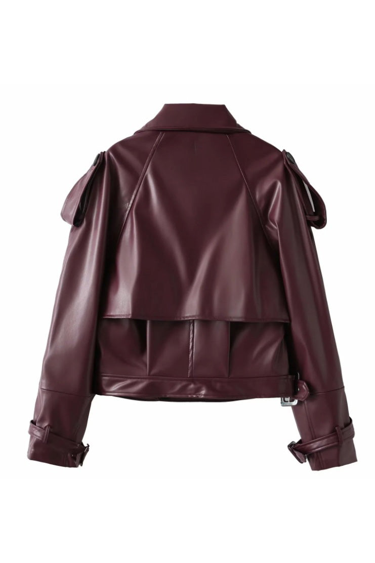 Red - A woman wearing a burgundy oversized faux leather jacket with wide lapels, belted cuffs, and voluminous sleeves, styled over a black turtleneck in a city setting.