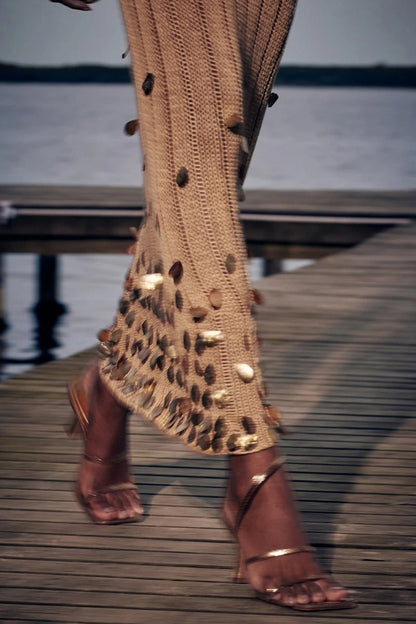 Yellow - Full-length view of a model wearing a long-sleeve, gold open-knit maxi dress with a plunging V-neckline, flared cuffs, and large gold sequin embellishments.