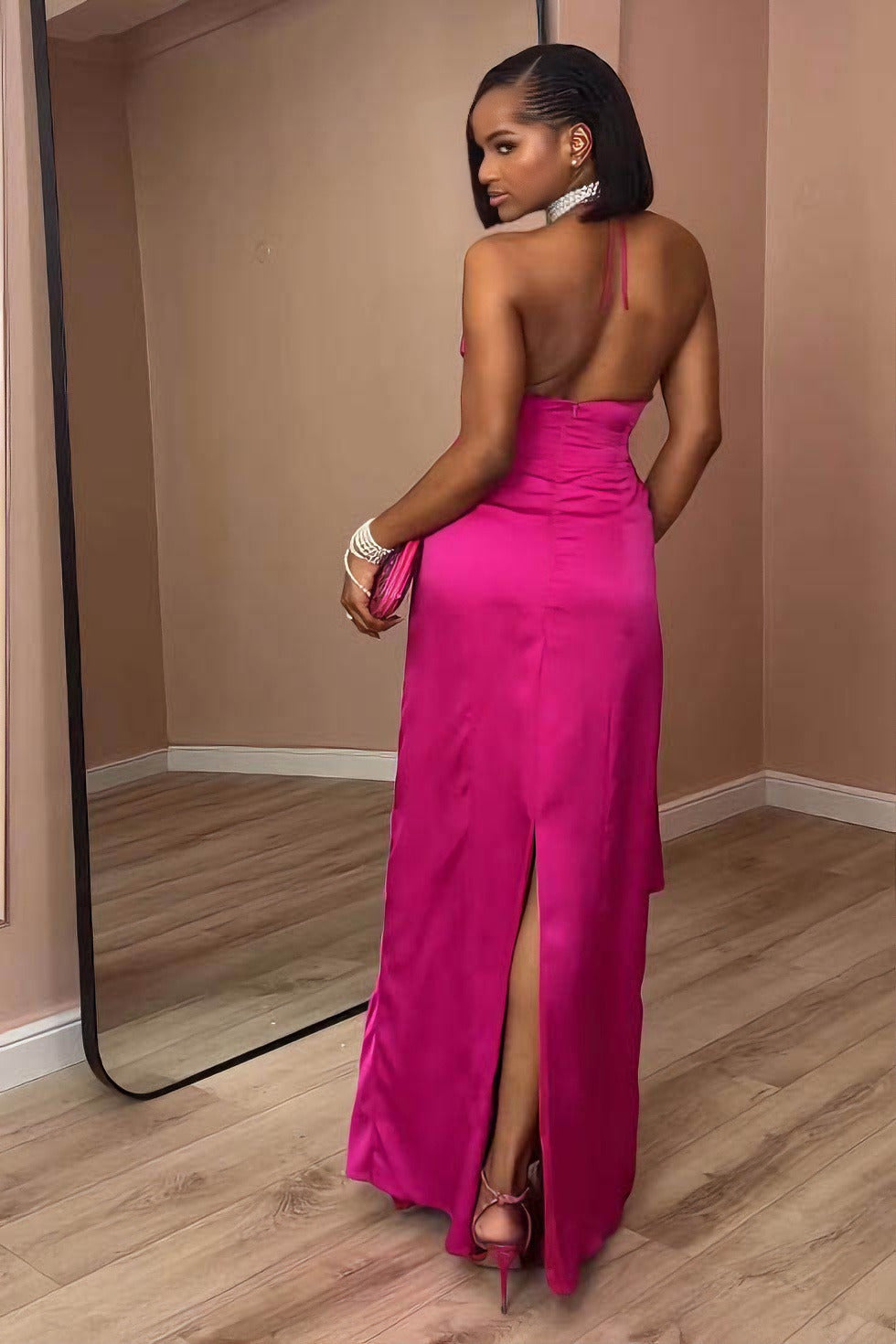 Pink - A woman modeling a formal, bright pink satin maxi gown featuring a halter neckline, a side cutout at the waist, and elegant draped detailing.