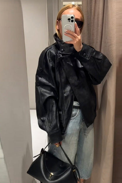 Black - A woman taking a mirror selfie wearing an oversized, black pebbled faux leather jacket with a high snap-button collar, dropped shoulders, and a cropped fit.