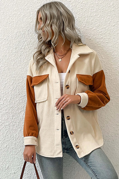 A woman wearing a relaxed fit, button-front shirt jacket featuring a cream body with contrasting rust orange sleeves and chest pocket flaps, styled open over a white crop top and jeans.