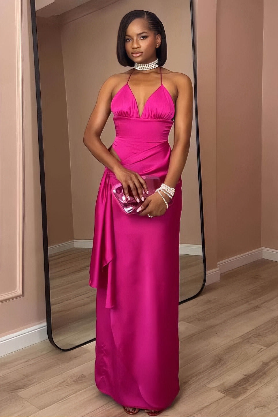 Pink - A woman modeling a formal, bright pink satin maxi gown featuring a halter neckline, a side cutout at the waist, and elegant draped detailing.