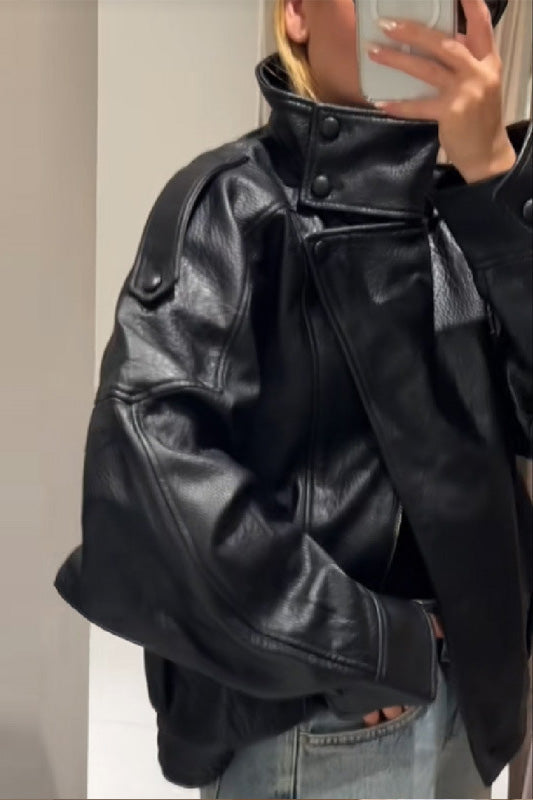 Black - A woman taking a mirror selfie wearing an oversized, black pebbled faux leather jacket with a high snap-button collar, dropped shoulders, and a cropped fit.